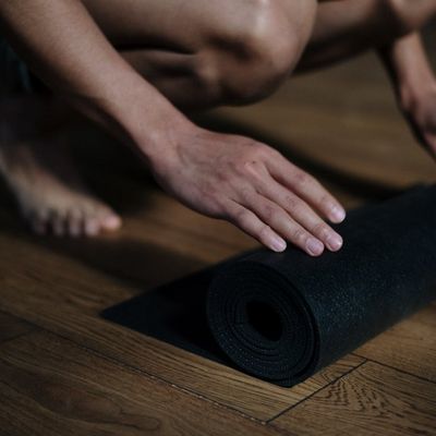 Green yoga mat on dark wooden floor